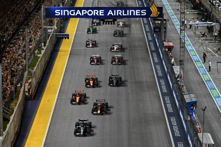 SINGAPORE, SINGAPORE - OCTOBER 05: George Russell of Great Britain driving the (63) Mercedes AMG Petronas F1 Team W16 leads Max Verstappen of the Netherlands driving the (1) Oracle Red Bull Racing RB21 and the rest of the field at the start prior to the F1 Grand Prix of Singapore at Marina Bay Street Circuit on October 05, 2025 in Singapore, Singapore. (Photo by Simon Galloway/LAT Images)